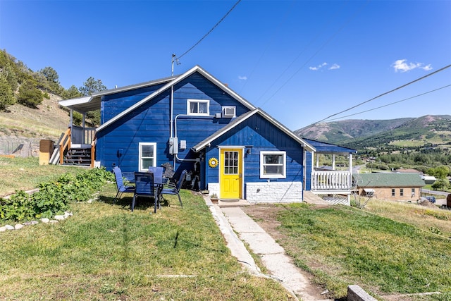 view of front of property with stone siding, a mountain view, and a front lawn