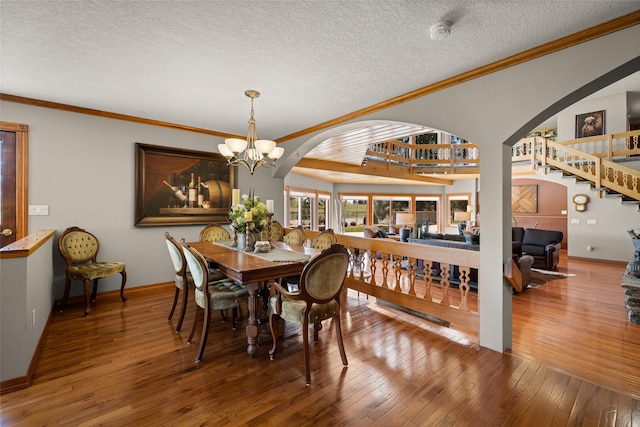 417 Sirucek Ln, Kalispell, MT 59901 - dining room featuring arched walkways, stairway, a textured ceiling, crown molding, and hardwood / wood-style flooring