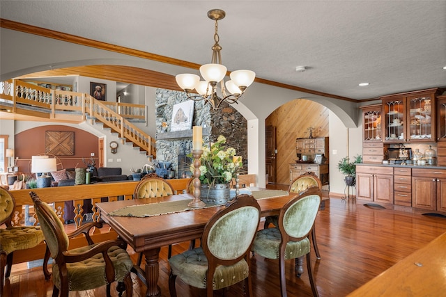417 Sirucek Ln, Kalispell, MT 59901 - dining room featuring arched walkways, a chandelier, wood finished floors, ornamental molding, and a textured ceiling