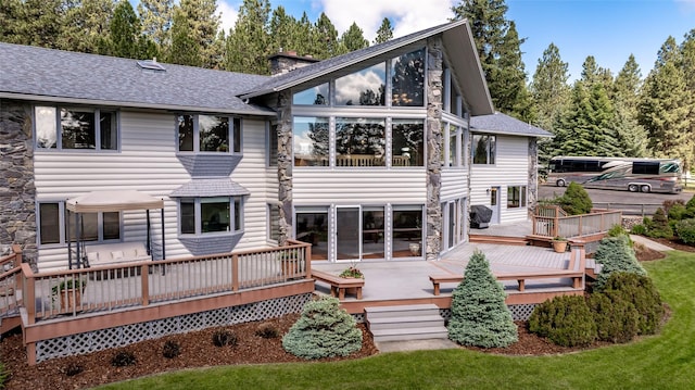 417 Sirucek Ln, Kalispell, MT 59901 - rear view of house with a shingled roof, stone siding, a chimney, and a deck