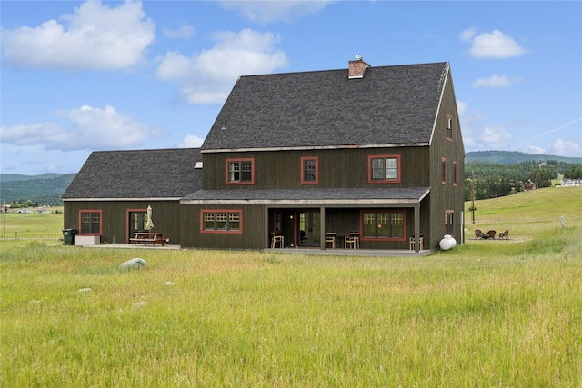 285 N Hill Rd, Kalispell, MT 59901 - rear view of property featuring a mountain view, roof with shingles, and a chimney