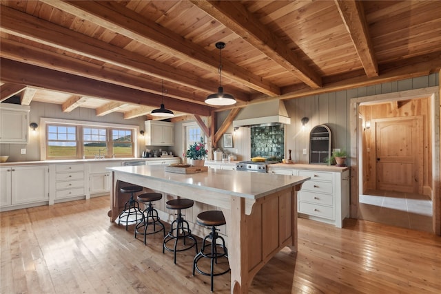 285 N Hill Rd, Kalispell, MT 59901 - kitchen with custom exhaust hood, a center island, a wood ceiling with exposed beams, light wood finished floors, and range