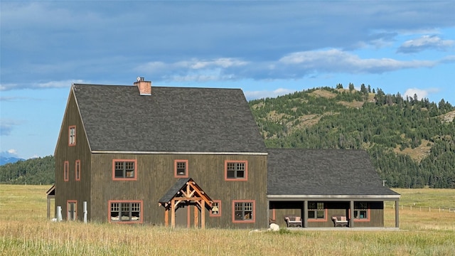 285 N Hill Rd, Kalispell, MT 59901 - view of front facade featuring a chimney, roof with shingles, and a wooded view