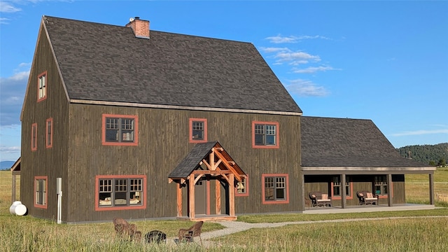 285 N Hill Rd, Kalispell, MT 59901 - rear view of house featuring roof with shingles, a chimney, a lawn, and a patio