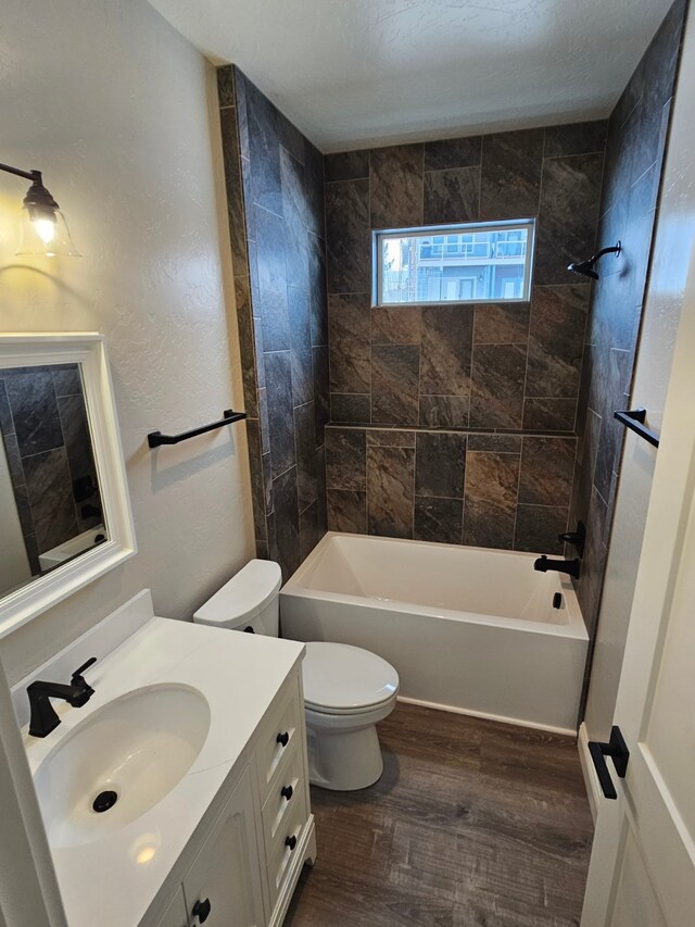 full bathroom featuring toilet, wood-type flooring, a textured ceiling, vanity, and tiled shower / bath combo