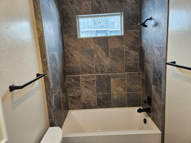 bathroom with tiled shower / bath combo and toilet