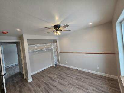 unfurnished bedroom featuring dark hardwood / wood-style floors, ceiling fan, and a closet