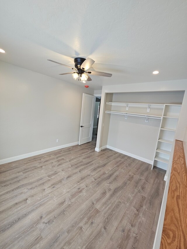 unfurnished bedroom with a textured ceiling, light hardwood / wood-style floors, a closet, and ceiling fan