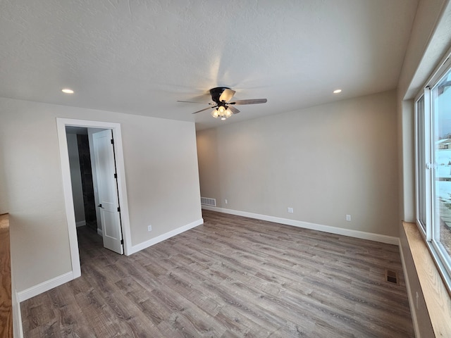 unfurnished room with a textured ceiling, light hardwood / wood-style floors, and ceiling fan