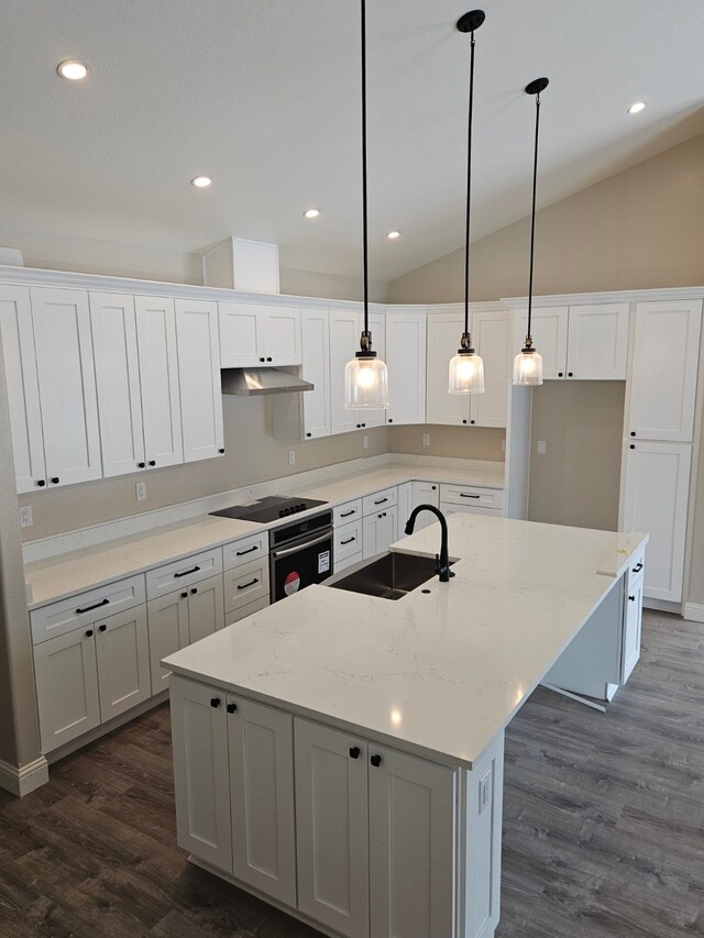 kitchen featuring decorative light fixtures, white cabinetry, sink, a kitchen island with sink, and light stone counters