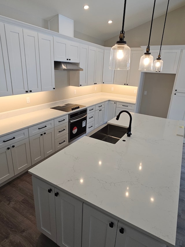 kitchen with white cabinetry, sink, light stone counters, and decorative light fixtures