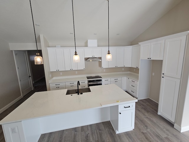 kitchen with sink, decorative light fixtures, an island with sink, and white cabinets