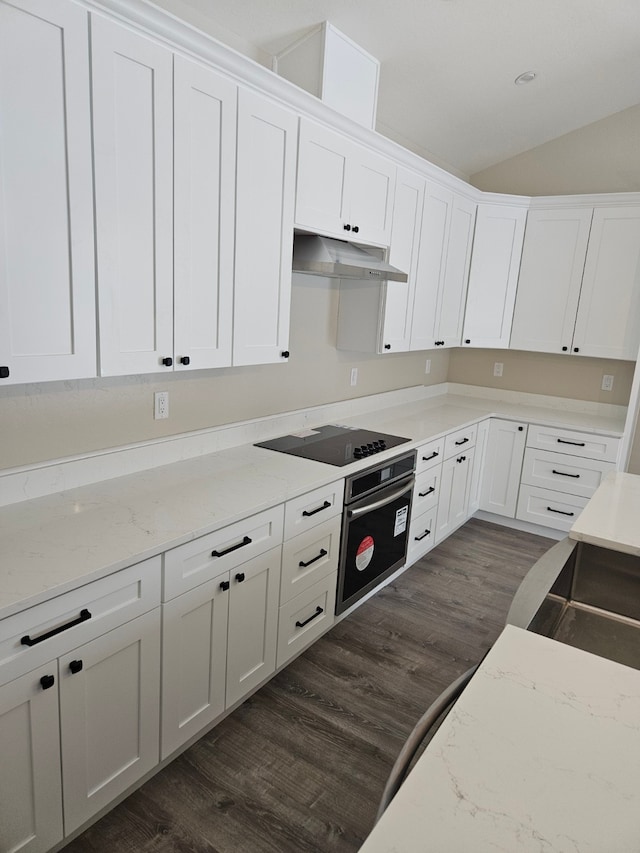 kitchen with vaulted ceiling, black electric cooktop, dark hardwood / wood-style floors, oven, and white cabinets