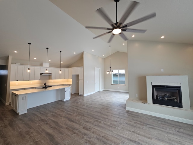 kitchen with sink, white cabinetry, decorative light fixtures, an island with sink, and ceiling fan with notable chandelier