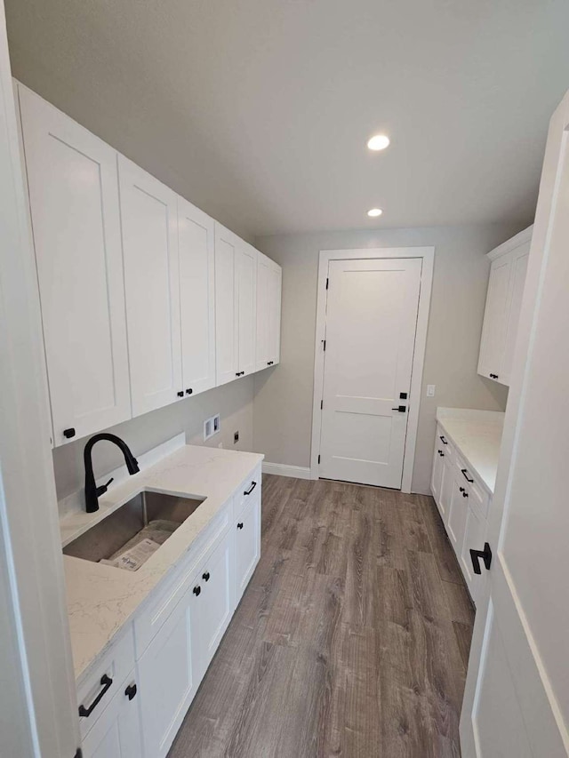 clothes washing area with sink, electric dryer hookup, cabinets, washer hookup, and light wood-type flooring