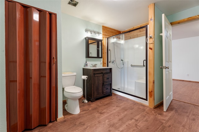 bathroom with toilet, a shower with shower door, hardwood / wood-style floors, and vanity