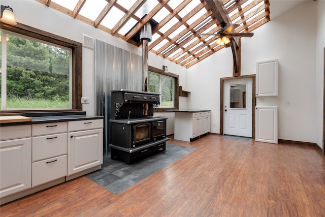 kitchen featuring ceiling fan, white cabinets, high vaulted ceiling, plenty of natural light, and dark hardwood / wood-style floors