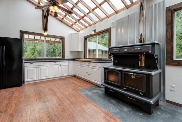 kitchen with white cabinetry, ceiling fan, hardwood / wood-style floors, beamed ceiling, and black fridge