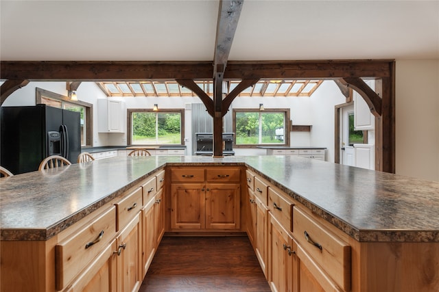 kitchen with dark hardwood / wood-style floors, beamed ceiling, a spacious island, and black fridge