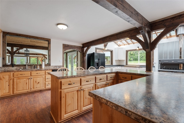 kitchen with tasteful backsplash, dark hardwood / wood-style flooring, black fridge, lofted ceiling with beams, and sink