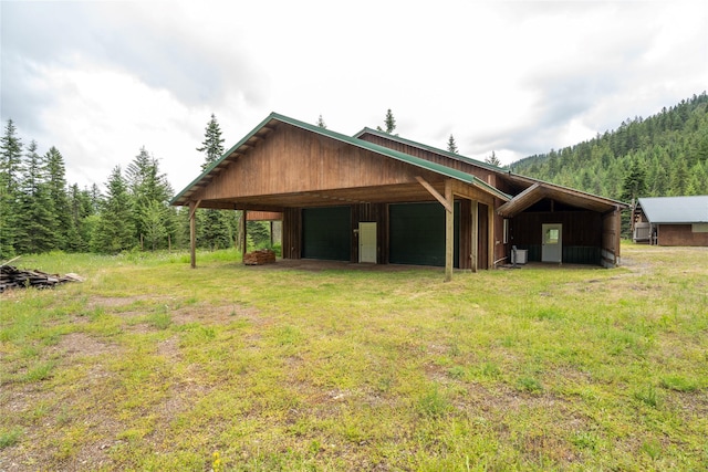 96 S Sanctuary Loop, Heron, MT 59844 - view of home's exterior featuring a garage, an outdoor structure, a view of trees, and a pole building