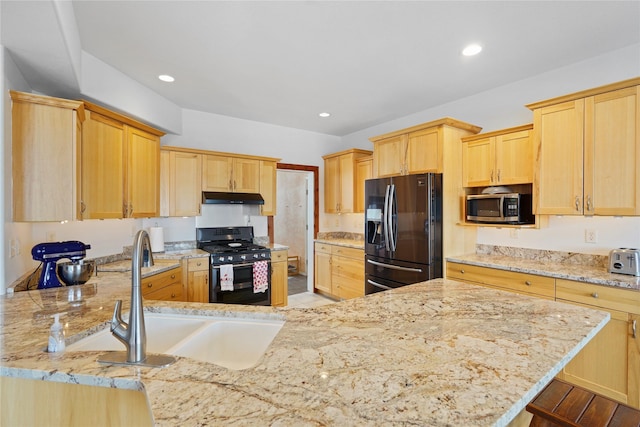 kitchen featuring sink, a kitchen bar, light stone counters, black appliances, and light brown cabinets