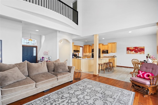 living room featuring a towering ceiling and light hardwood / wood-style flooring