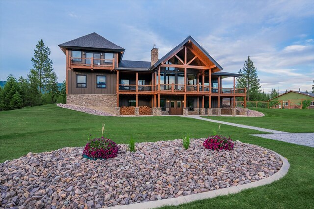 rear view of house featuring a yard and a balcony