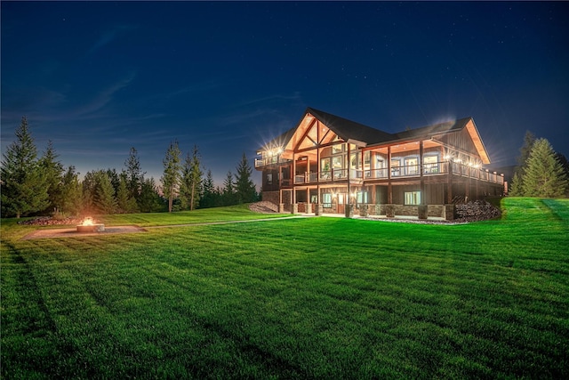 back of property featuring a deck, an outdoor fire pit, and a lawn