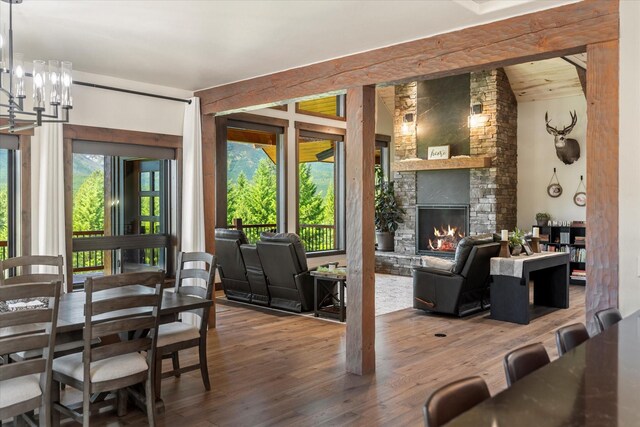 dining area featuring a chandelier, wood-type flooring, and a stone fireplace