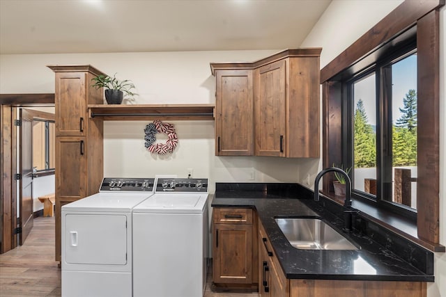 washroom featuring washing machine and dryer, sink, light hardwood / wood-style floors, and cabinets