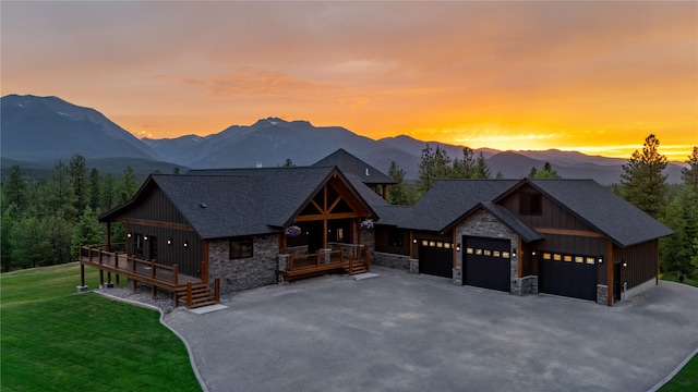 view of front facade with a garage, a deck with mountain view, and a lawn