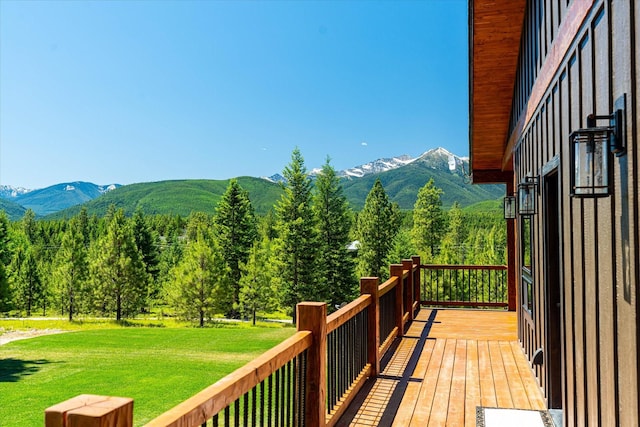 wooden terrace featuring a mountain view and a lawn