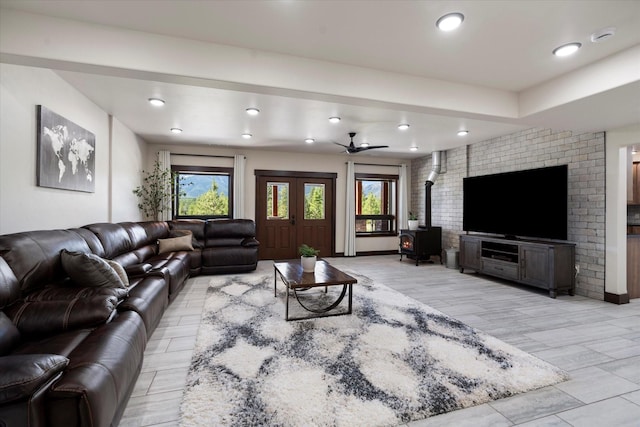 living room with ceiling fan, a wood stove, and light hardwood / wood-style flooring