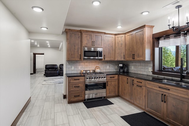 kitchen featuring sink, hanging light fixtures, appliances with stainless steel finishes, and tasteful backsplash