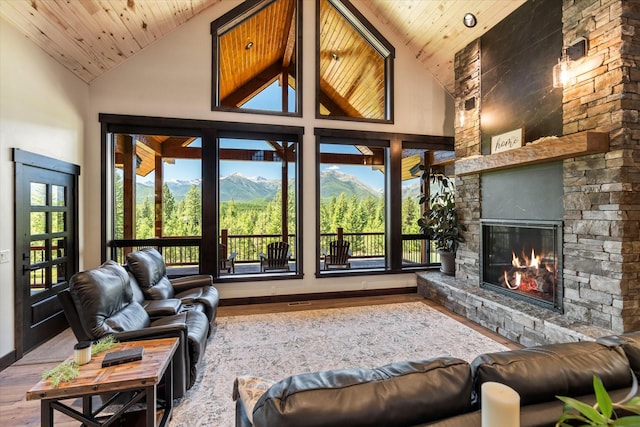 living room with wood ceiling, a mountain view, hardwood / wood-style floors, a stone fireplace, and high vaulted ceiling