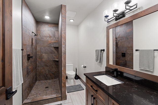 bathroom with toilet, vanity, and a tile shower