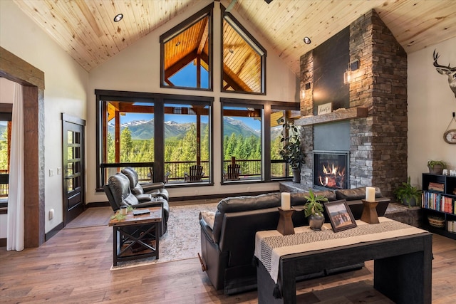 living room with a mountain view, high vaulted ceiling, a stone fireplace, and wood ceiling