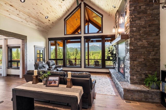 living room with wooden ceiling, a stone fireplace, and high vaulted ceiling