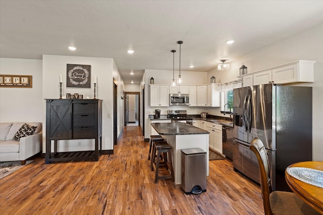 kitchen with white cabinetry, appliances with stainless steel finishes, a kitchen breakfast bar, a kitchen island, and pendant lighting