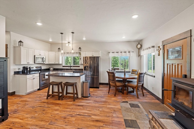 kitchen featuring decorative light fixtures, a center island, a kitchen bar, sink, and appliances with stainless steel finishes