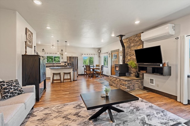 living room featuring an AC wall unit, a wood stove, and light hardwood / wood-style flooring