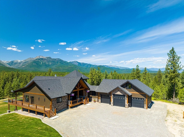 view of front of property featuring a front yard, a garage, and a deck with mountain view