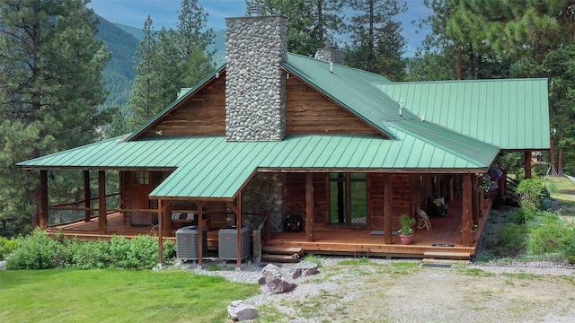 rear view of house featuring a mountain view, a porch, a lawn, and central air condition unit