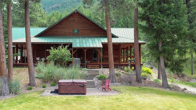 exterior space with a hot tub and a lawn