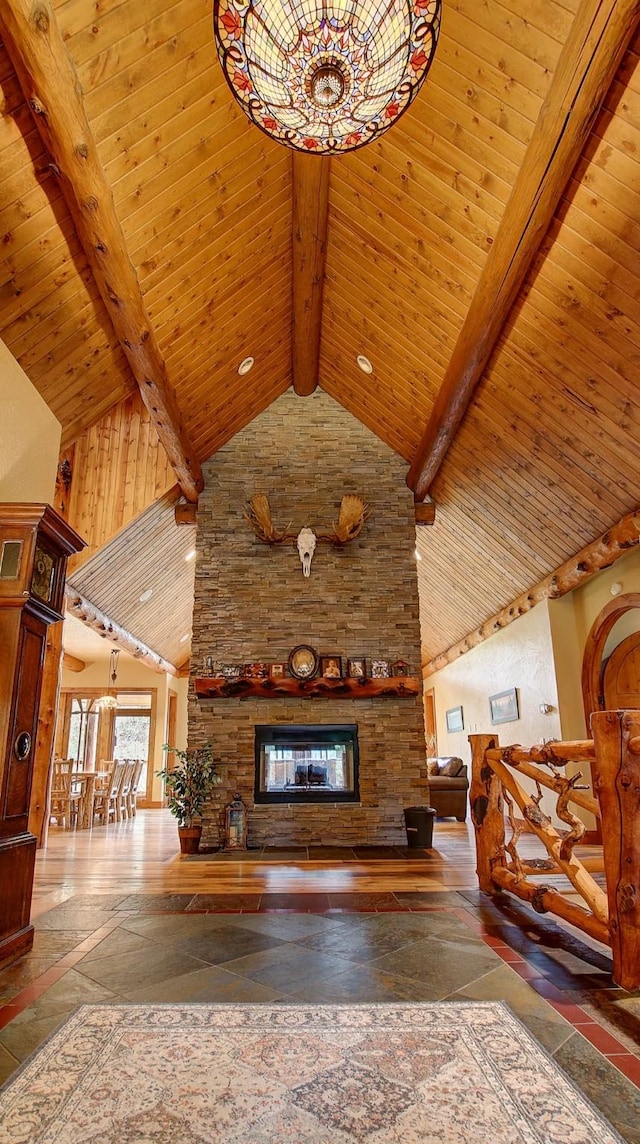 unfurnished living room with a stone fireplace, beamed ceiling, wood ceiling, and high vaulted ceiling