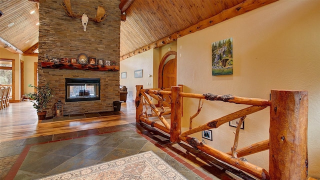 staircase featuring a stone fireplace, wooden ceiling, and a high ceiling