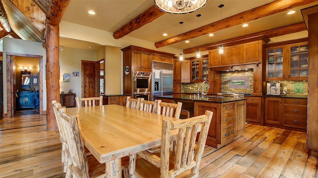 dining room with beamed ceiling, light hardwood / wood-style floors, an inviting chandelier, and sink