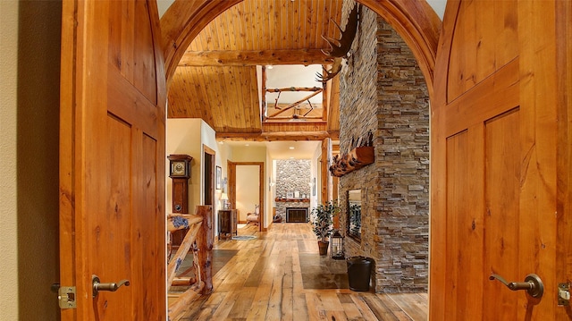 corridor featuring beam ceiling, wood-type flooring, and a high ceiling