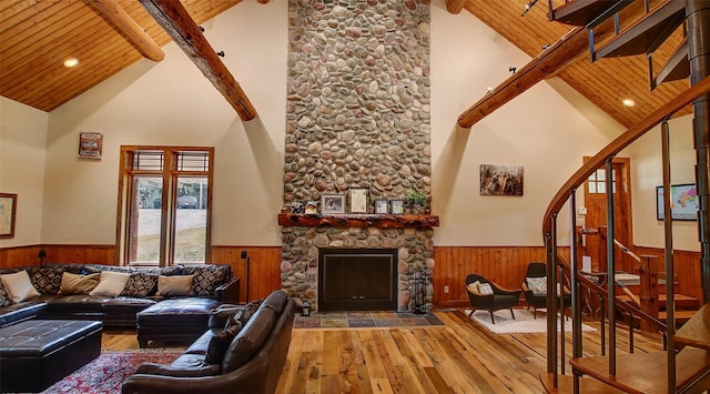 living room with beam ceiling, a stone fireplace, high vaulted ceiling, and wooden ceiling